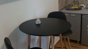 Una cocina pequeña con una mesa de comedor y sillas, un televisor montado en la pared y un salpicadero de azulejos.