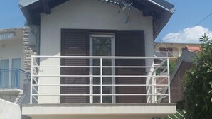 Una casa de dos pisos con balcón, cochera y valla metálica.