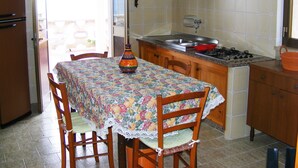 Una cocina con una mesa de comedor, sillas, estufa y armarios.