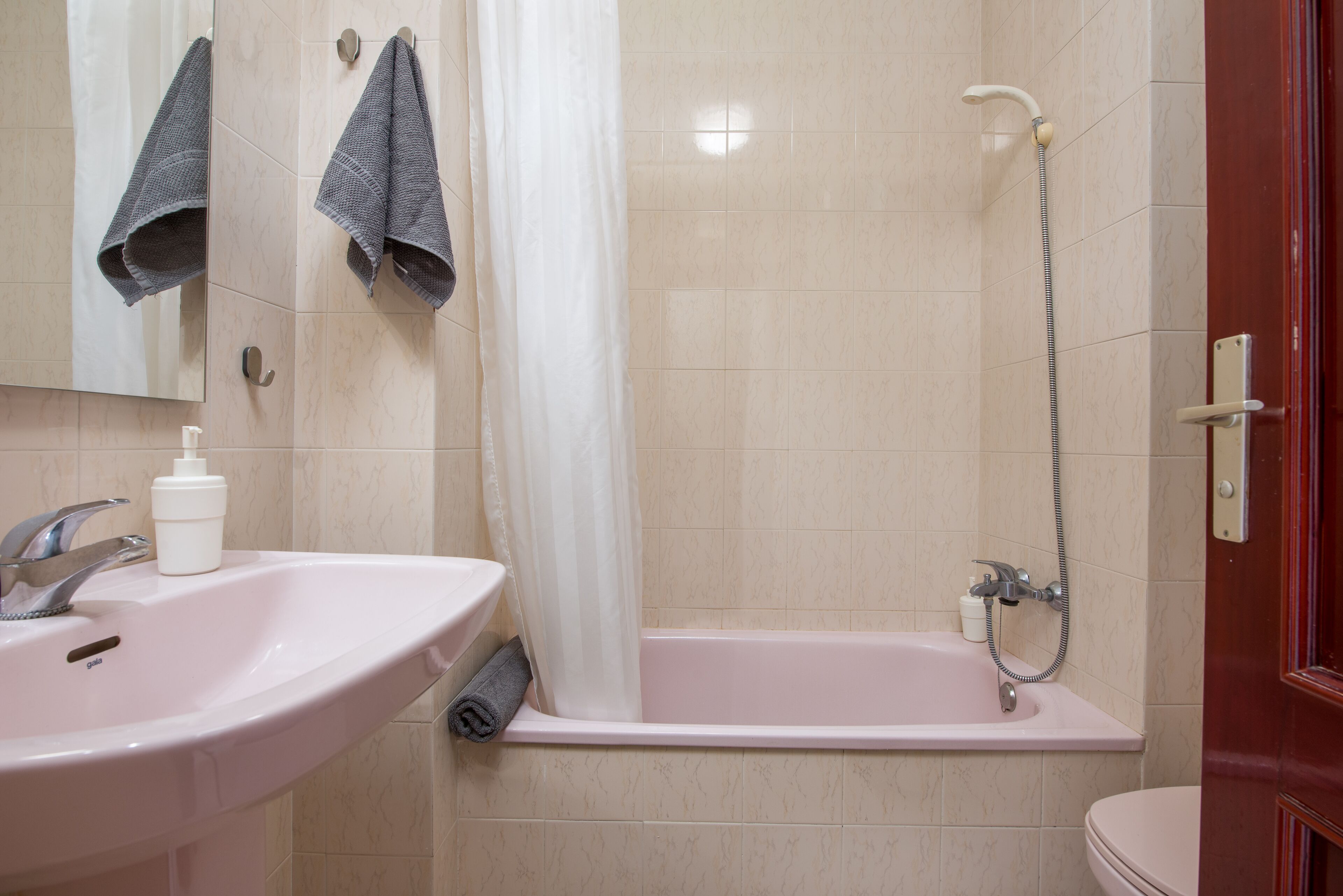 Une salle de bain équipée d’un lavabo, d’un miroir, d’une douche et de toilettes.