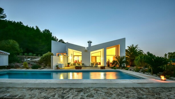 Ein modernes Haus mit Swimmingpool, Sitzgelegenheiten im Freien und einer Steinterrasse.