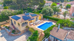 A villa with a swimming pool, solar panels, and a garden.