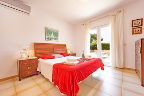 A bedroom with a bed, a nightstand, a dresser, a window with curtains, and a painting on the wall.
