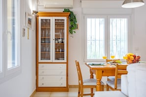 A dining area with a wooden cabinet, a table with chairs, and a window with decorative iron bars.