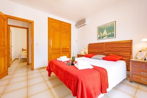 A hotel room with a large bed, wooden wardrobe, and a painting on the wall.