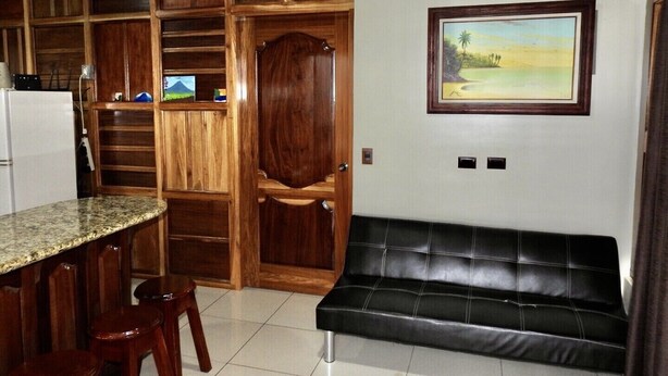 Una cucina con mobili in legno, un frigorifero integrato, una zona pranzo con piano di lavoro in marmo e una panca in pelle nera.