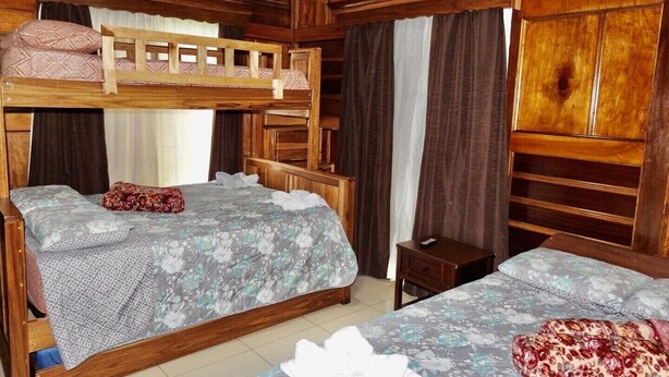 A room with two bunk beds, a small wooden nightstand, and a large wardrobe. - Bosque Alto House (La Fortuna)