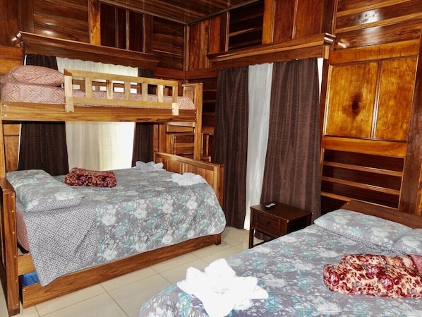 A room with two bunk beds, a small wooden nightstand, and a large wardrobe. - Bosque Alto House (La Fortuna)