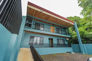 A two-story building with a balcony, a staircase, and a view of the surrounding greenery. - Bosque Alto House (La Fortuna)