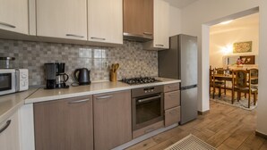 A modern kitchen with a microwave, coffee maker, gas stove, oven, and refrigerator.