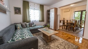 A modern living room with a sectional sofa, a coffee table, and a dining area with a wooden table and chairs.