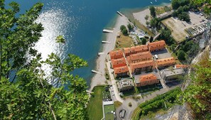 A coastal hotel with multiple red-roofed buildings, a beach, and a marina. - Campione Giulia Exclusive Lakefront (Campione del Garda)
