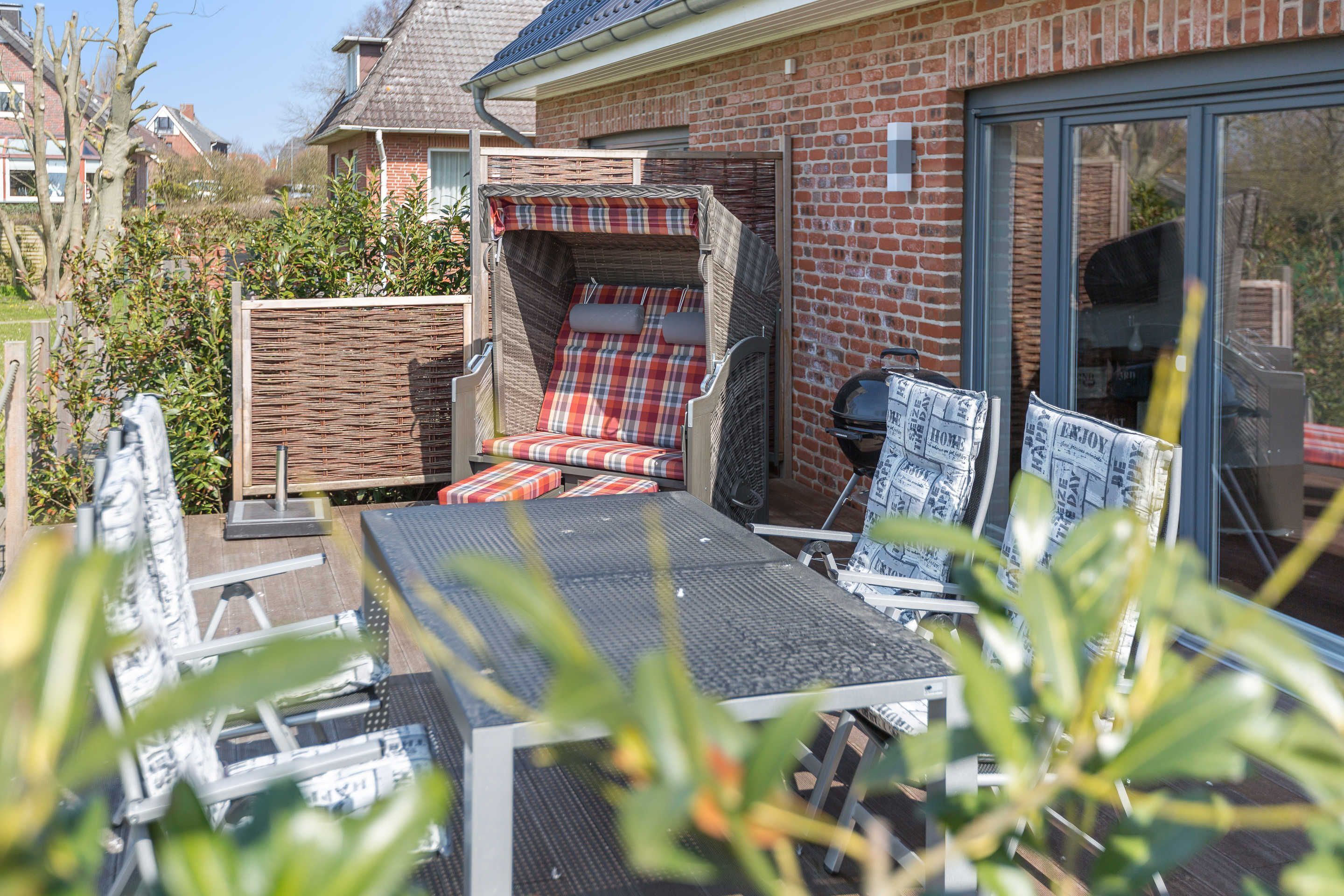 Un patio con zona de estar techada, una mesa y una parrilla.