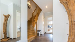 A modern interior with a wooden staircase, a dining area, and a large tree trunk decoration. - Fehmarn - Fehmarn in List on Sylt (List)