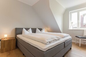 A modern bedroom with a bed, bedside table, and a window with a view.