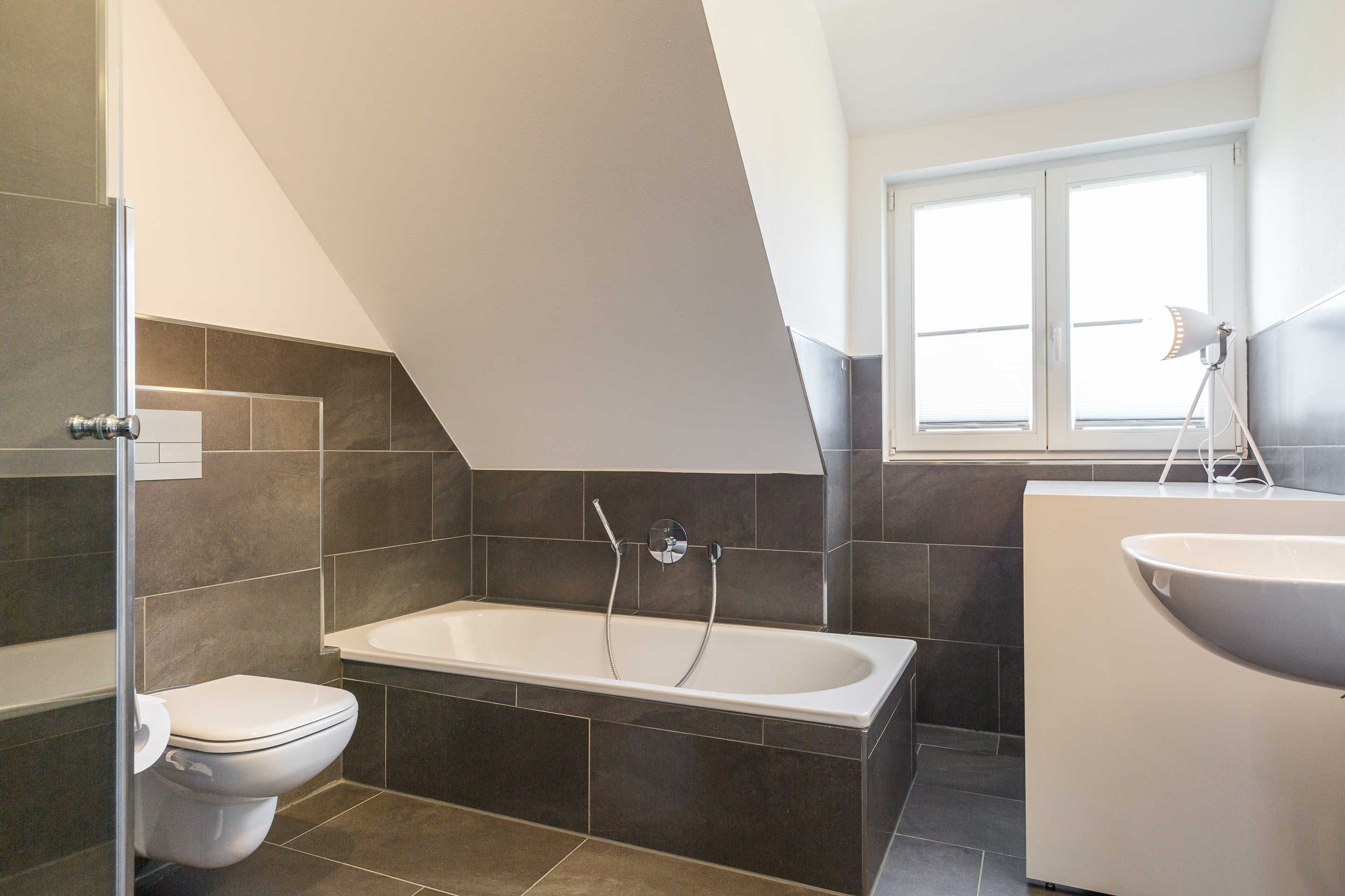 A modern bathroom with a bathtub, toilet, and sink.