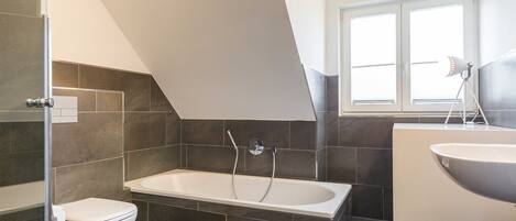 A modern bathroom with a bathtub, toilet, and sink.