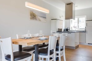 A modern kitchen with white cabinets, a wooden dining table, and black chairs.