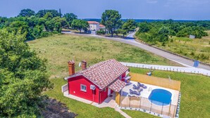 Uma casa vermelha com piscina e varanda coberta.