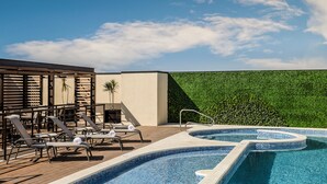 A rooftop pool area with lounge chairs and a green wall. - Fiesta Inn Express Queretaro Constituyentes (Querétaro)
