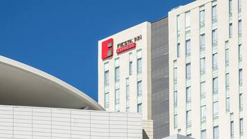 A hotel with a modern facade, a prominent red logo, and multiple windows.
