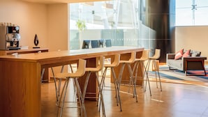 A modern kitchen with a long island, bar stools, and a coffee machine. - Fiesta Inn Express Queretaro Constituyentes (Querétaro)