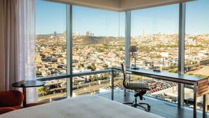 A hotel room with a large window offering a city view, a desk with a chair, and a bed. - Fiesta Inn Express Queretaro Constituyentes (Querétaro)