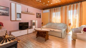 Un salón acogedor con techo de madera, un televisor de pantalla plana, un sofá y una mesita decorativa.
