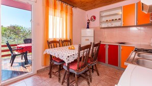 Un comedor con una mesa preparada para cuatro, un refrigerador y una cocina con armarios rojos y un lavabo.