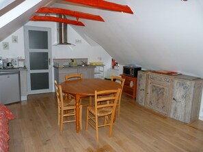 Une petite cuisine accueillante, avec une table et des chaises en bois, un four à micro-ondes et un réfrigérateur.