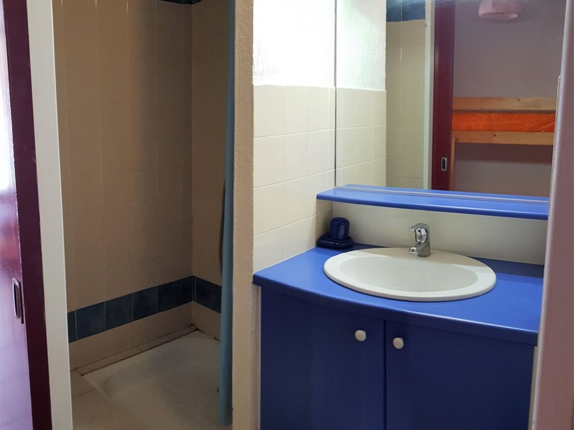 A bathroom with a blue sink, white tiles, and a mirror above it.