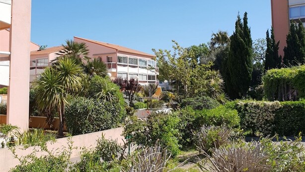A multi-story building with balconies, surrounded by lush greenery and palm trees. - Cozy Studio-Cabin, Pool Access, 200m from Beach, Sleeps 4 - Argelès-sur-Mer (Argelès-sur-Mer)