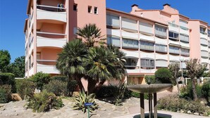 A multi-story building with balconies, a palm tree, and a small pool with a fountain. - Cozy Studio-Cabin, Pool Access, 200m from Beach, Sleeps 4 - Argelès-sur-Mer (Argelès-sur-Mer)