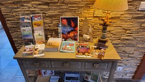 A display table with travel guides and books, a decorative lamp, and a stone wall background. - Magnificent chalet in Hohrod/Munster Alsace with panoramic south-facing view  (Hohrod)