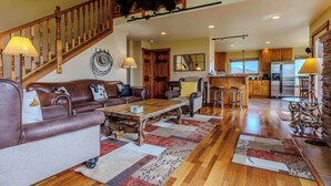 A spacious living room with a wooden staircase, a dining area, and a kitchen. - Yellowstone Trail Lodge · Yellowstone National park (Emigrant)