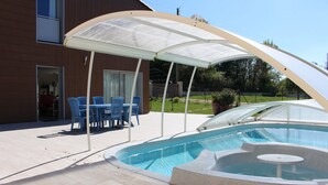 A swimming pool with a covered area, blue chairs, and a table. - Beautiful house 170 m2, heated and covered swimming pool, jacuzzi, classified 4 stars. (Laruscade)