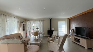 A spacious living room with a sofa, armchairs, a TV, and a fireplace. - Beautiful house 170 m2, heated and covered swimming pool, jacuzzi, classified 4 stars. (Laruscade)
