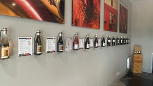 Un mur orné de bouteilles de vin et de fiches d’information, une boîte en bois et un sol carrelé.
