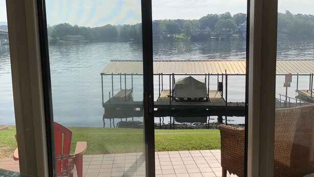 Une pièce dotée d’une grande porte-fenêtre coulissante donnant sur un patio aménagé avec du mobilier d’extérieur et offrant une vue sur un lac.