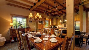 Un comedor espacioso con una mesa de madera dispuesta para una comida, rodeada de sillas de madera.