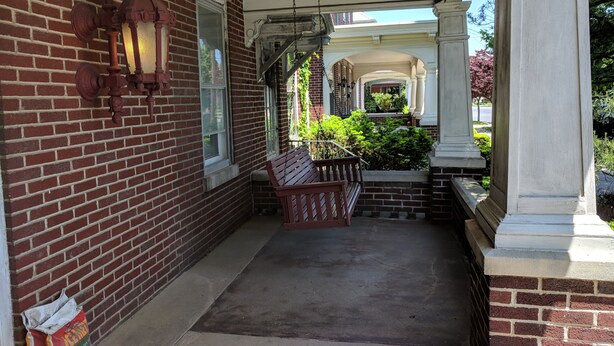 A covered porch with a bench, brick walls, and a view of a garden. - Cozy family home, close to all things Hershey and Central Pennsylvania... (Palmyra)