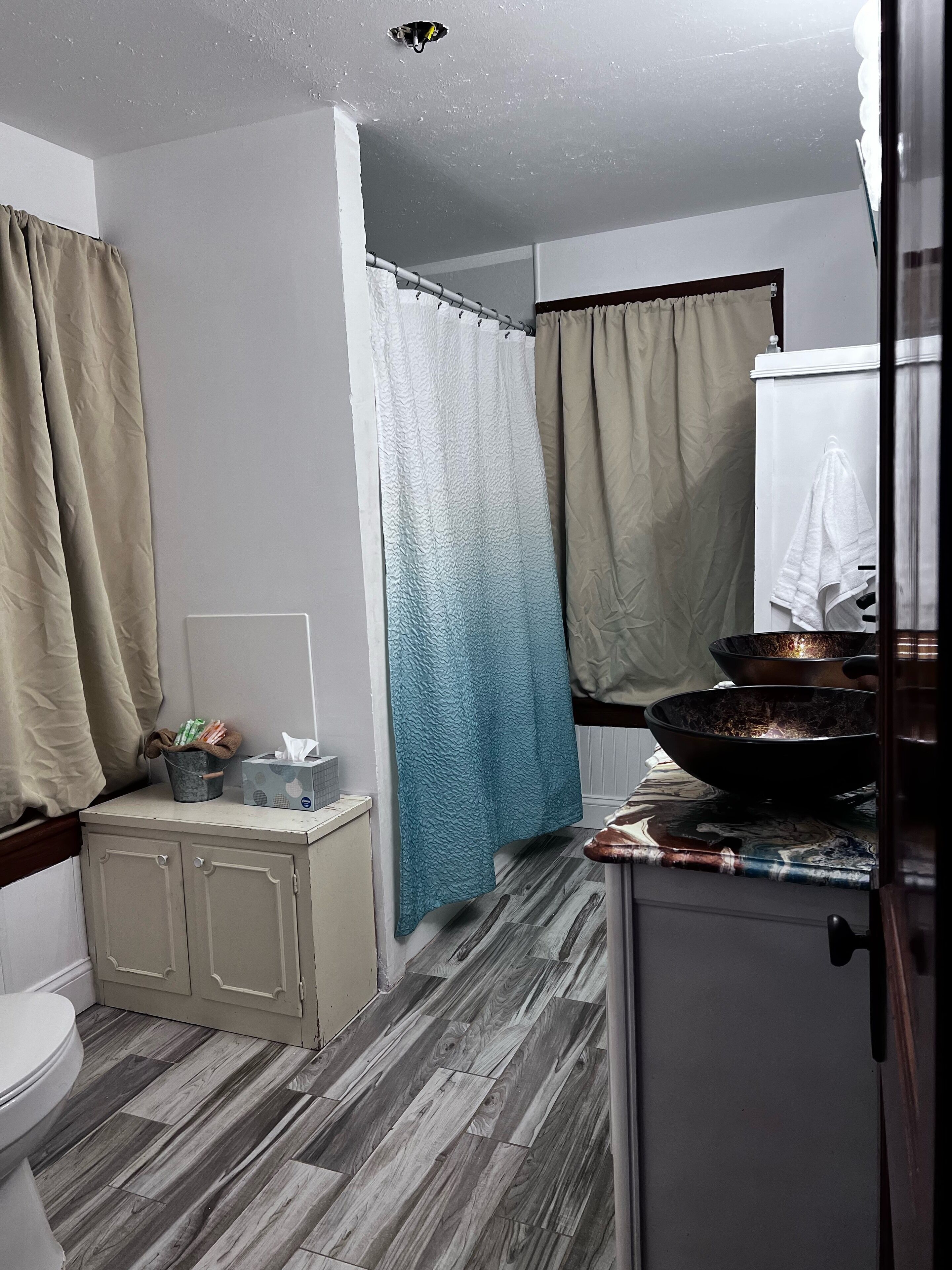 A bathroom with a toilet, a sink, a mirror, a towel hanging on the wall, and a shower curtain.
