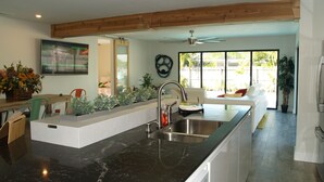 A modern kitchen with a black marble countertop, a built-in sink, and a ceiling fan.