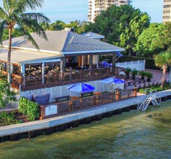 A waterfront restaurant with outdoor seating, a covered area, and a view of the water.