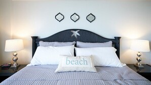 Una cama bien hecha con un cojín que dice "playa" y un adorno de estrella en la cabecera.