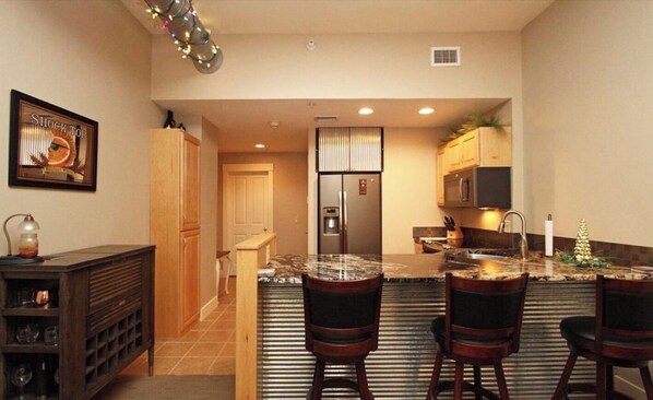 A modern kitchen with a central island, wooden cabinets, and a refrigerator.