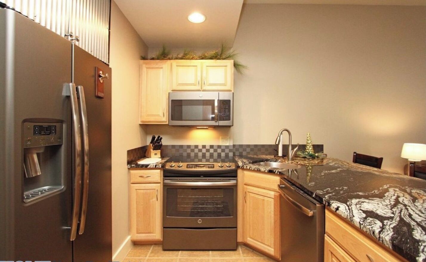 Cocina compacta con refrigerador, microondas, horno y encimera de granito.