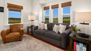 A cozy living room with a gray sofa, a leather armchair, and a "WELCOME" sign. - Snohomish Fobes Farmhouse built:1918  (Snohomish)