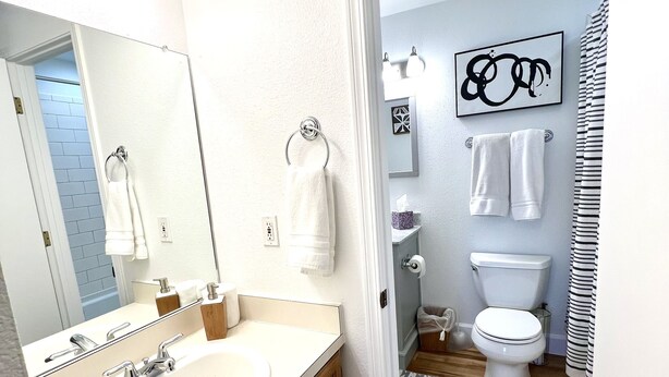 A modern bathroom with a large mirror, two sinks, a toilet, and a shower area. - Modern 2 Bedrooms, 1 Bathroom Apartment (Fort Collins)