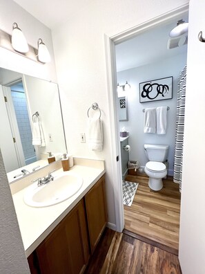 Een bad/douchecombinatie, een haardroger, handdoeken, zeep